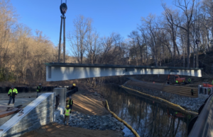 The span for a bike bridge over Rock Creek near the Zoo hangs from a crane over the creek