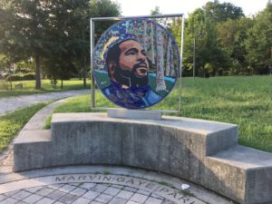 A mosaic of Marvin Gaye stands next to a trail and lots of green grass