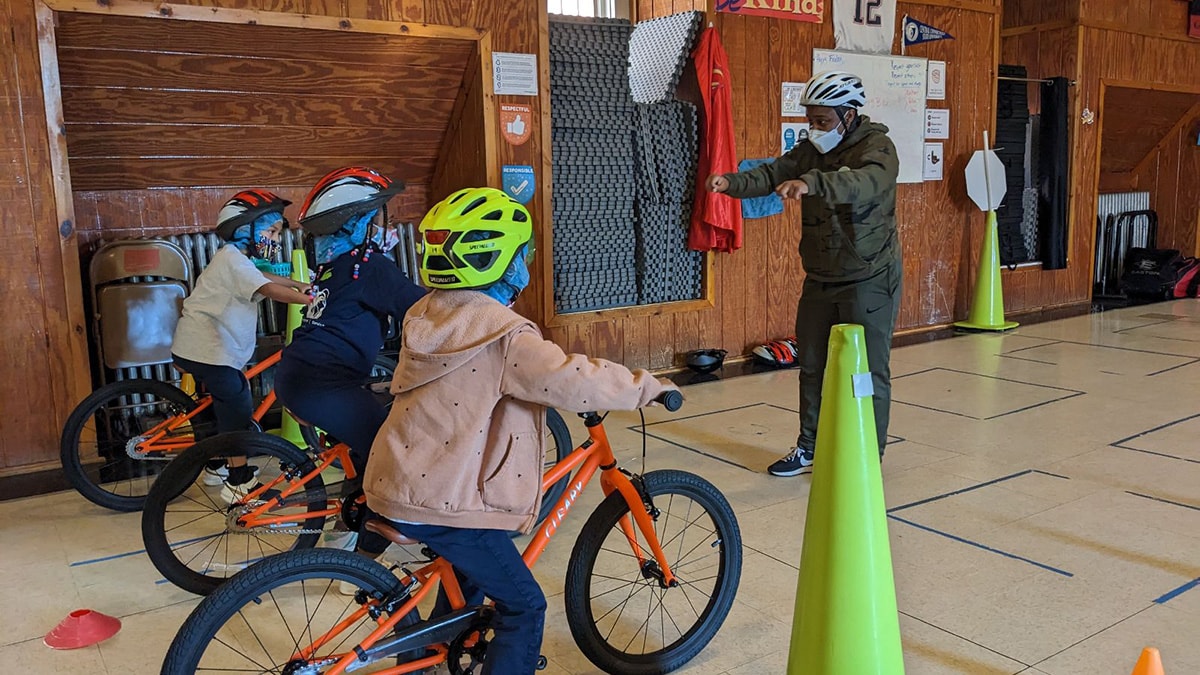 a WABA instructor encourages three students to practice gliding their bikes