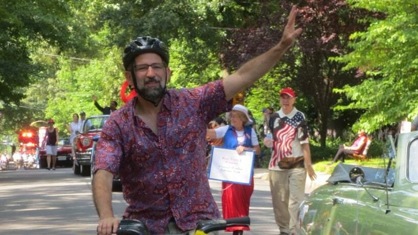 Seth rides a Capital Bike Share bike and waves during the 2014 Takoma Park 4th of July parade.