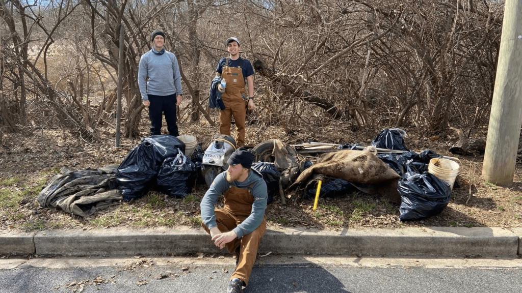 Trail rangers pose next to a pile of trash collected on the Hayes Street bikeway.