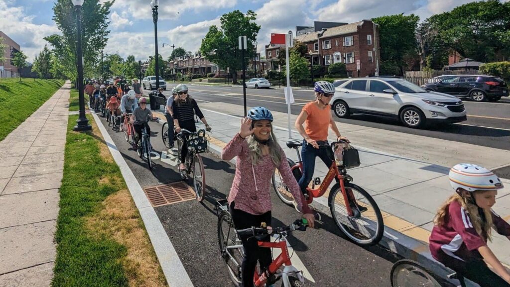 many adults and kids on bikes riding in a protected bike lane