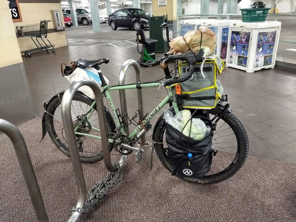 A bike with grocery bags spilling out of the panniers.