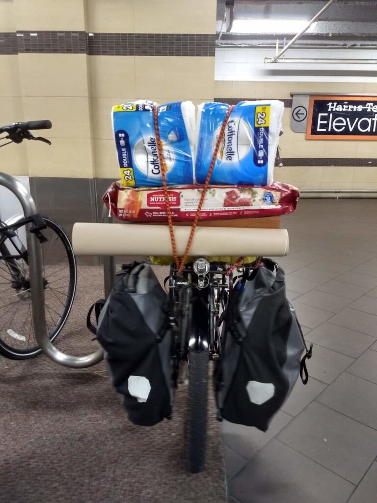 A bike mostly obscured by the load of groceries bungeed to the front rack.