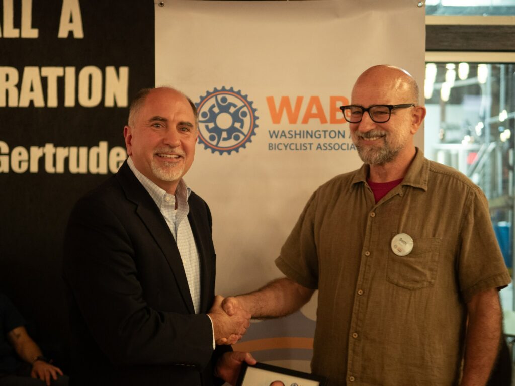 WABA Maryland Organizer Seth Grimes presented a Public Leadership Award  to Councilmember Eric Olson and a Community Advocate Award to Dan Behrend at the 2024 WABA Awards program